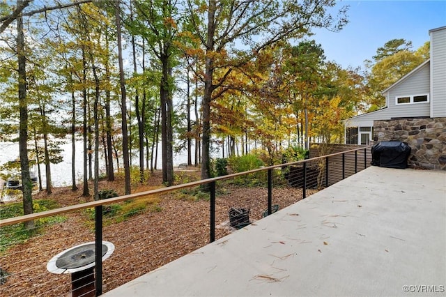 exterior space featuring fence, a water view, and area for grilling