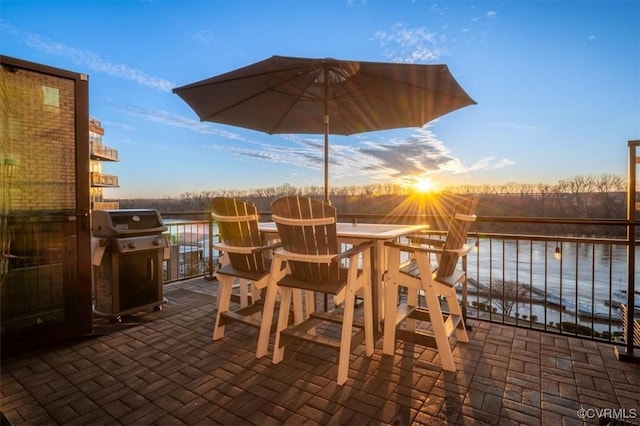 view of patio featuring a water view, outdoor dining area, and a grill