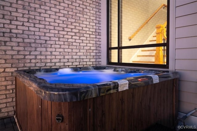 exterior space featuring a hot tub and brick siding