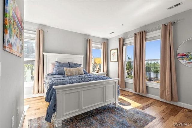 bedroom with baseboards, visible vents, and wood finished floors