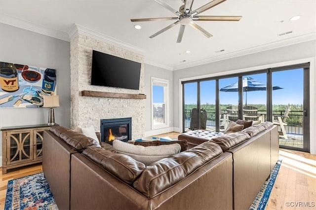 living room with a ceiling fan, recessed lighting, a stone fireplace, and light wood-type flooring