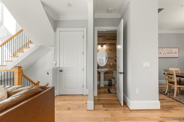 interior space featuring baseboards, ornamental molding, and light wood-type flooring