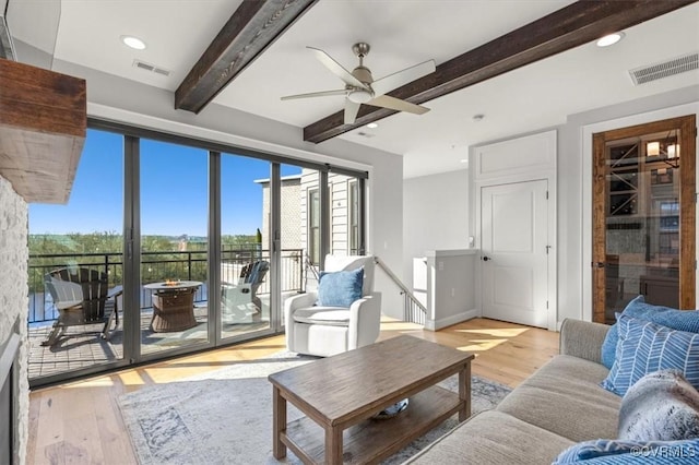living room with visible vents, beam ceiling, and light wood-type flooring