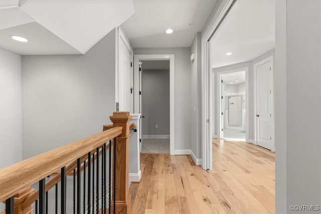 hallway featuring recessed lighting, baseboards, light wood finished floors, and an upstairs landing