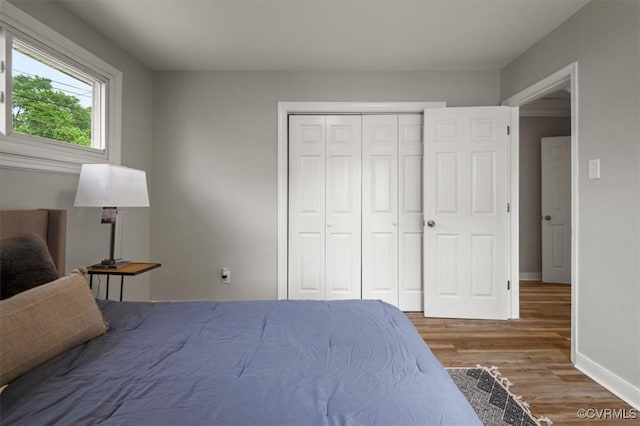 bedroom featuring baseboards, wood finished floors, and a closet