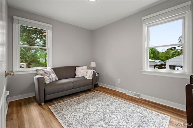 living area featuring baseboards, light wood finished floors, and visible vents