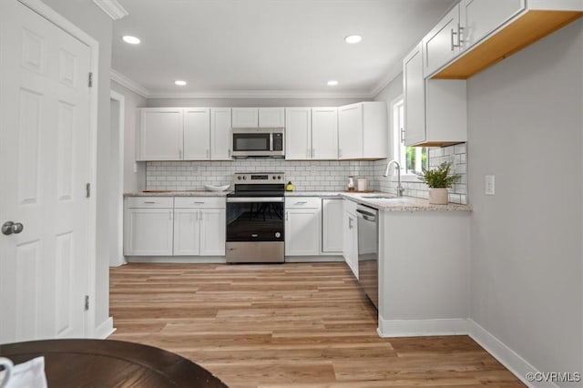kitchen featuring crown molding, appliances with stainless steel finishes, a sink, white cabinetry, and light wood-type flooring