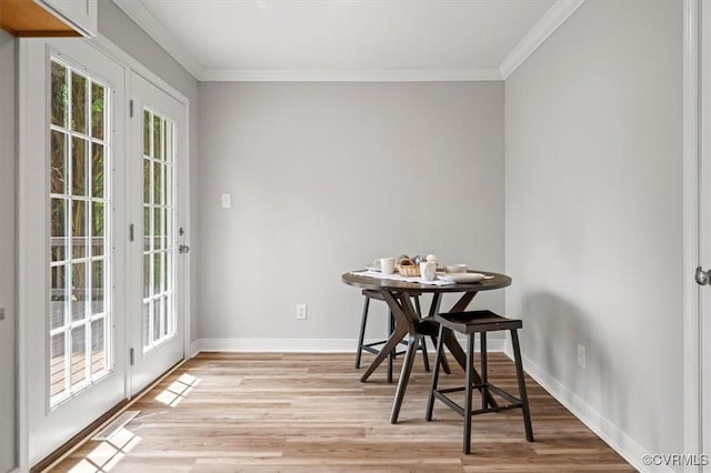 dining space featuring baseboards, light wood-style flooring, and crown molding