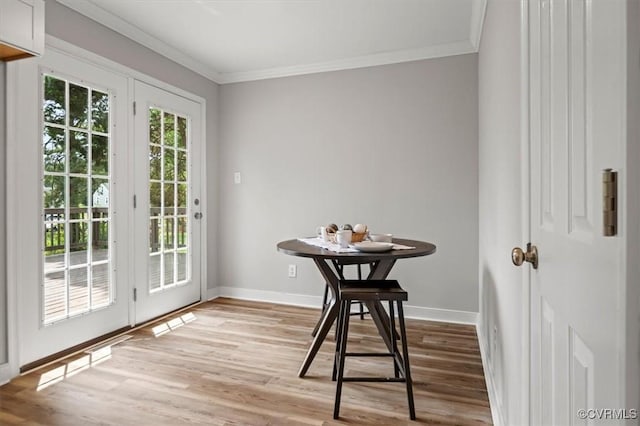 dining room featuring crown molding, baseboards, and light wood-type flooring