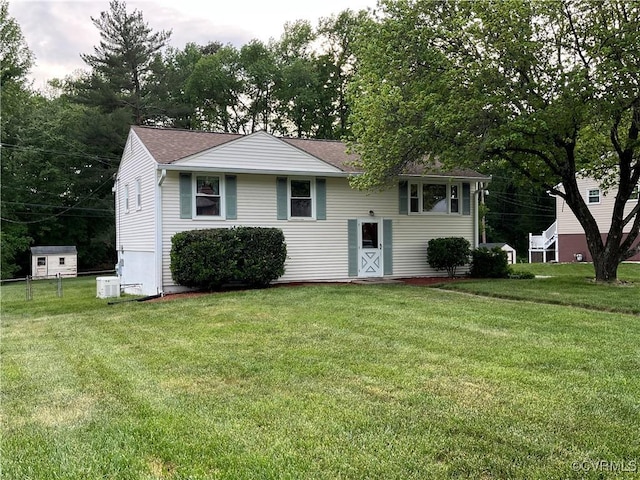 bi-level home featuring roof with shingles, central AC, and a front yard
