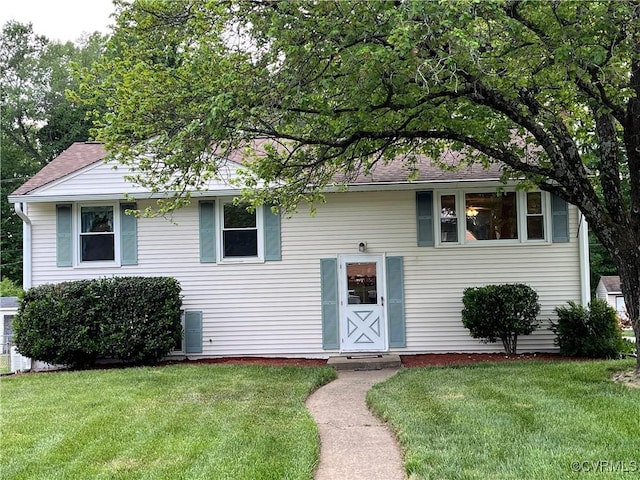bi-level home with a shingled roof and a front yard