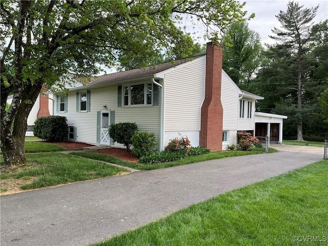 view of side of property featuring a chimney, a yard, and driveway