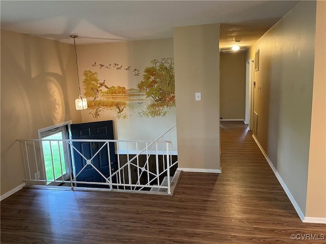 interior space featuring baseboards, an upstairs landing, and wood finished floors