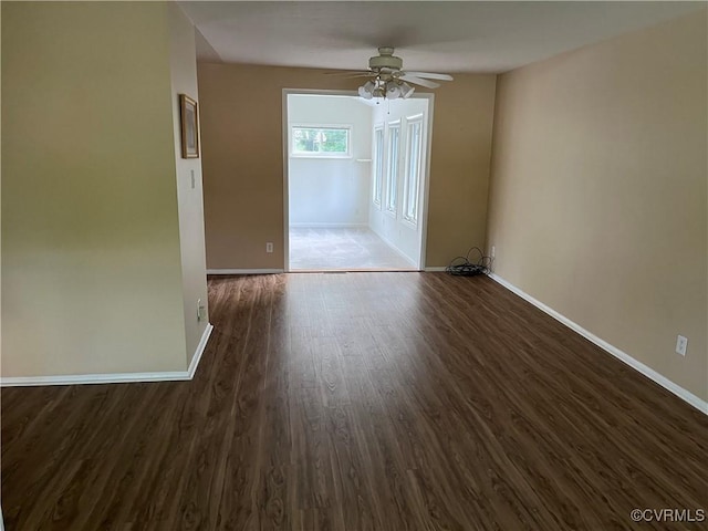 unfurnished room featuring baseboards, ceiling fan, and dark wood-style flooring