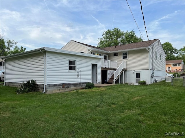 rear view of house with a lawn, fence, a deck, and stairway
