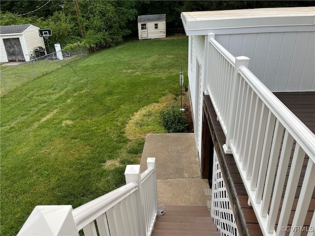 view of yard with a deck, fence, an outbuilding, and a shed
