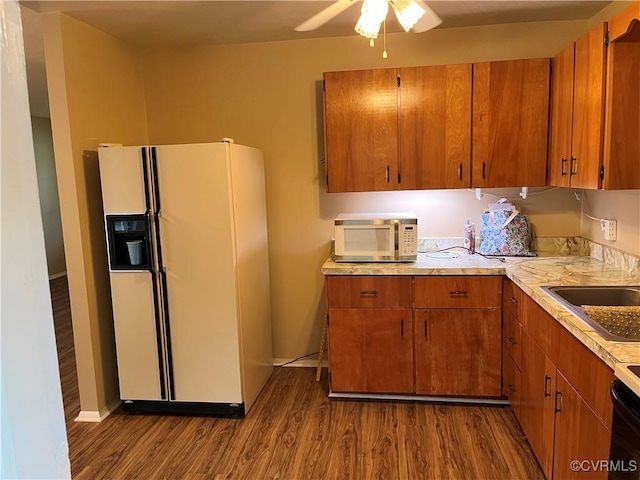 kitchen with white appliances, light countertops, brown cabinetry, a ceiling fan, and dark wood-type flooring