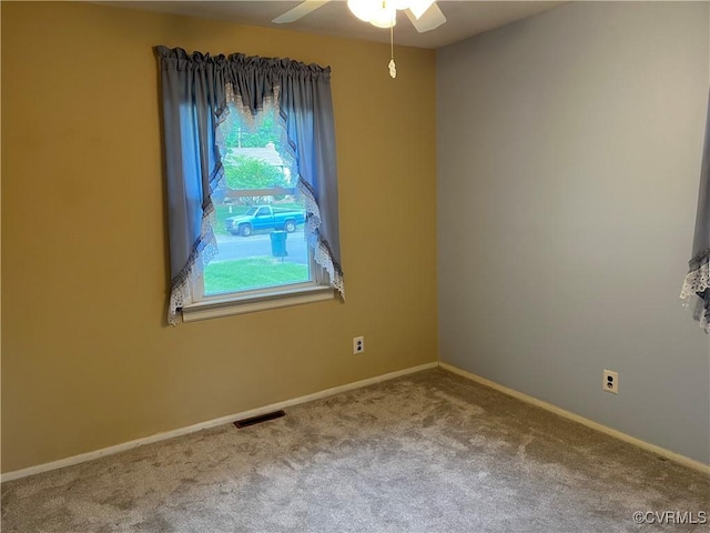 empty room with carpet floors, baseboards, ceiling fan, and visible vents