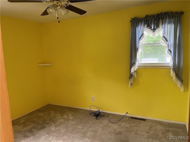 carpeted spare room with visible vents, a ceiling fan, and baseboards