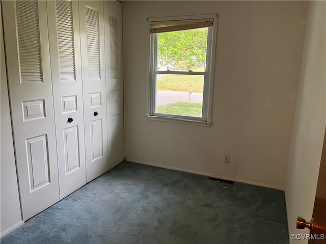 unfurnished bedroom featuring a closet, baseboards, multiple windows, and carpet flooring