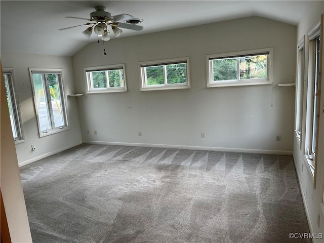 empty room featuring carpet floors, baseboards, ceiling fan, and vaulted ceiling