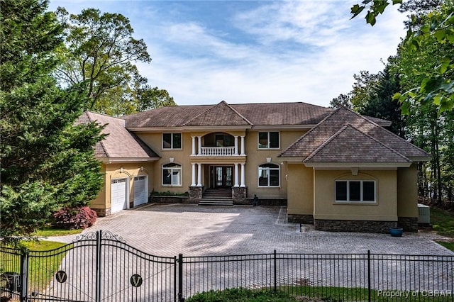 view of front of house with french doors, stucco siding, an attached garage, and fence private yard