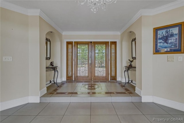 foyer with crown molding, arched walkways, tile patterned flooring, baseboards, and a notable chandelier