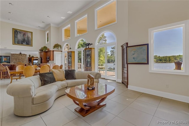 living room featuring baseboards, a high ceiling, ornamental molding, and light tile patterned floors