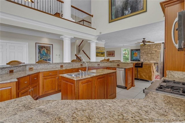 kitchen with ceiling fan, a kitchen island with sink, a sink, stainless steel microwave, and light tile patterned flooring