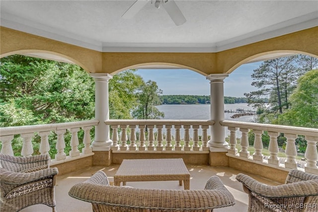balcony with a water view and a ceiling fan