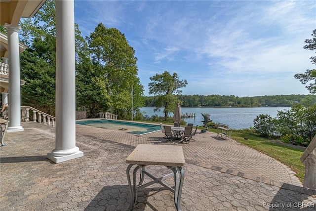 pool featuring a water view, a patio area, and outdoor dining space
