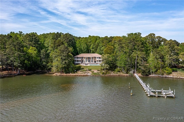 property view of water featuring a boat dock and a forest view