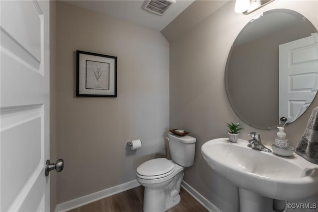 bathroom with visible vents, wood finished floors, toilet, baseboards, and a sink