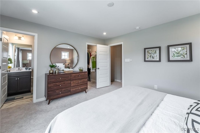 bedroom with a walk in closet, light carpet, recessed lighting, and connected bathroom