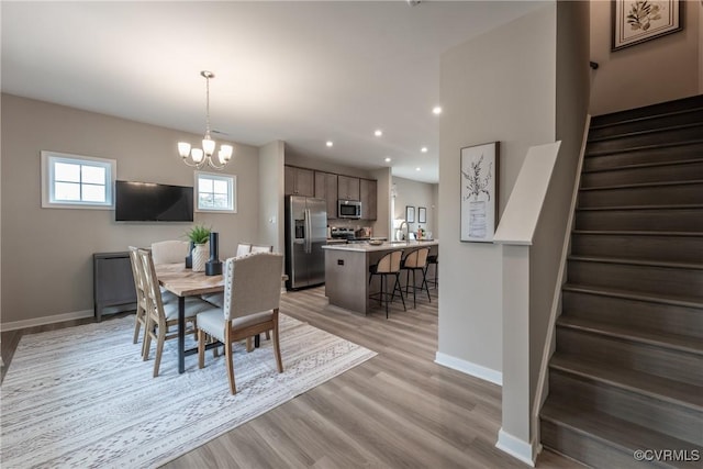 dining space featuring stairs, baseboards, recessed lighting, a chandelier, and light wood-style flooring