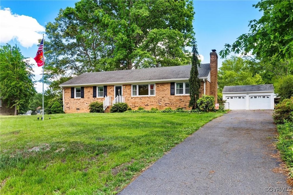 single story home featuring a chimney, an outbuilding, brick siding, a front yard, and a detached garage