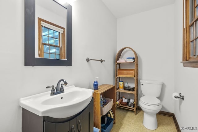 half bathroom with vanity, baseboards, vaulted ceiling, and toilet