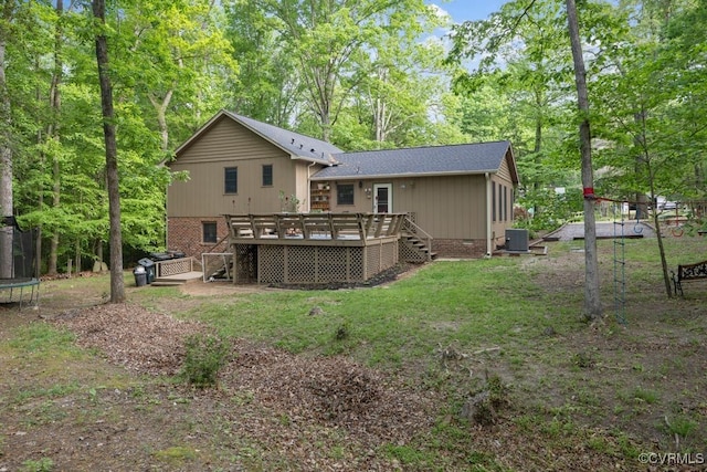 rear view of property featuring central air condition unit, a deck, stairs, and a trampoline