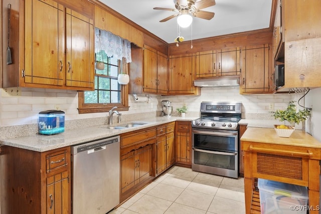 kitchen with a sink, brown cabinetry, stainless steel appliances, and under cabinet range hood