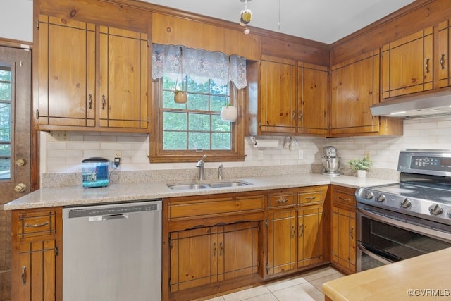 kitchen with a sink, appliances with stainless steel finishes, under cabinet range hood, and brown cabinets