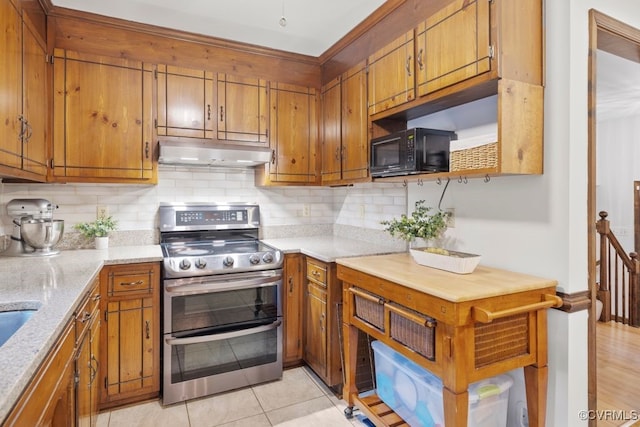 kitchen with backsplash, range with two ovens, black microwave, brown cabinets, and under cabinet range hood