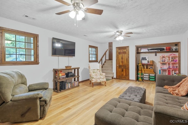 living room featuring wood finished floors, a ceiling fan, a textured ceiling, and visible vents