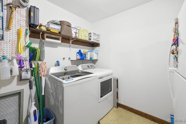 clothes washing area featuring separate washer and dryer, laundry area, and baseboards