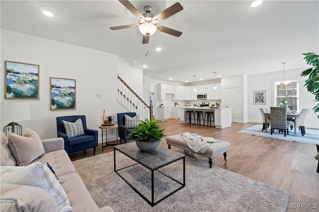 living room with a ceiling fan, recessed lighting, light wood-style flooring, and stairway
