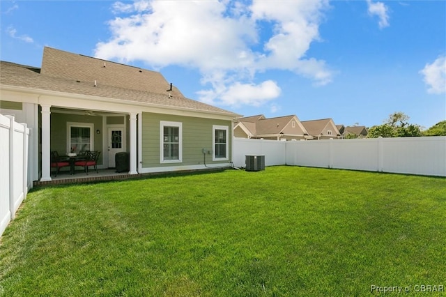 rear view of house with a yard, central AC, and a fenced backyard