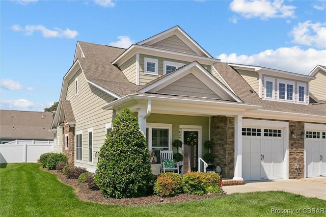 craftsman-style house featuring fence, a front lawn, driveway, and roof with shingles