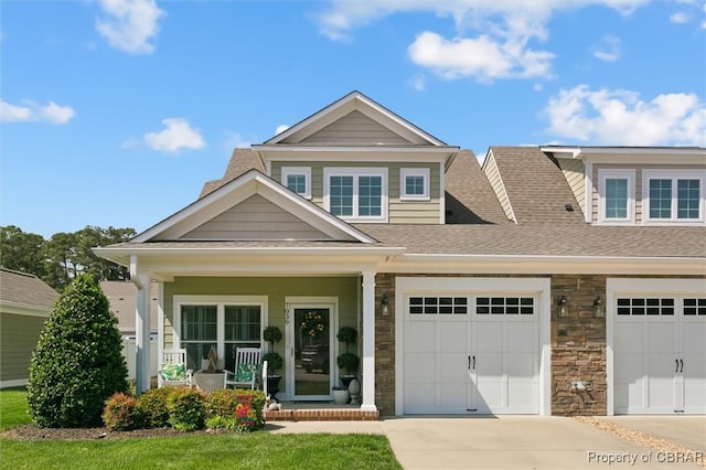 craftsman house with covered porch, driveway, a shingled roof, and stone siding