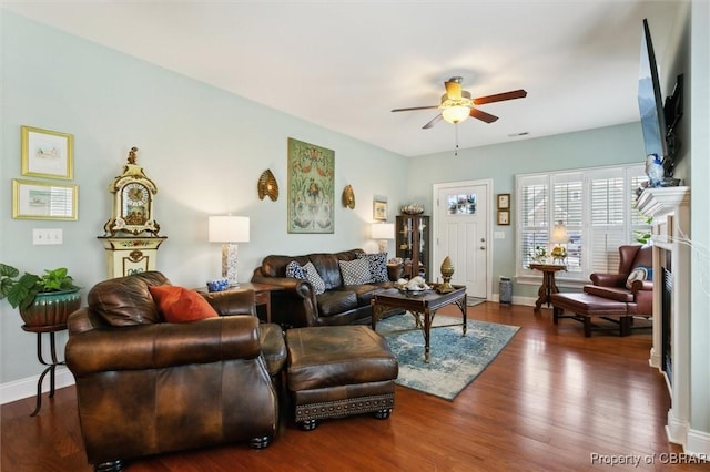 living area with a ceiling fan, baseboards, and wood finished floors