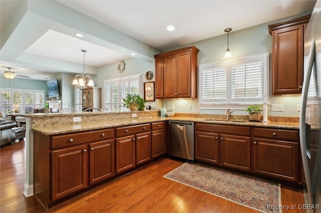 kitchen featuring dark wood-style flooring, appliances with stainless steel finishes, a sink, a peninsula, and open floor plan