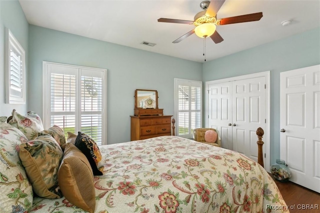 bedroom with multiple windows, a closet, wood finished floors, and visible vents